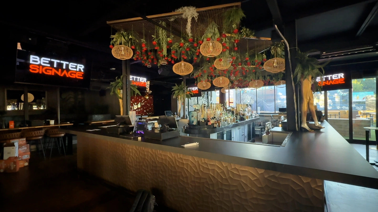 Bar interior with venue visuals playing on multiple mounted TVs